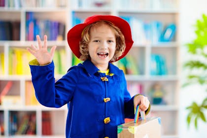 Boy dressed in blue raincoat and red hat for Paddington Bear costume