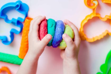 Child playing with red, green and blue playdough