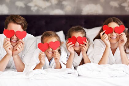Family lying in bed with paper hearts