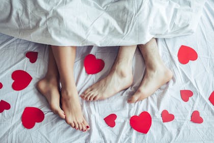 couple in bed surrounded by red hearts