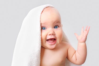 Smiling baby wearing a towel on their head