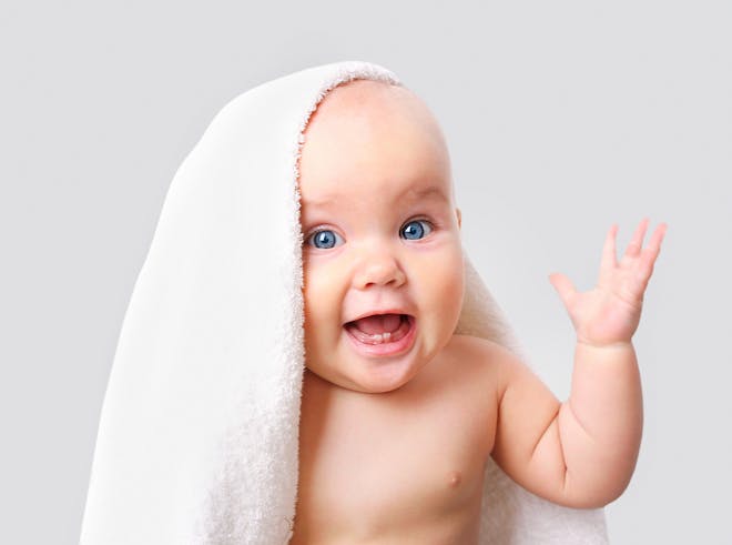 Smiling baby wearing a towel on their head