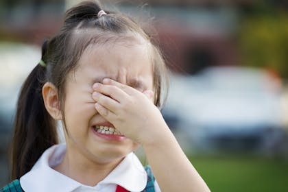 Young girl crying wearing school uniform