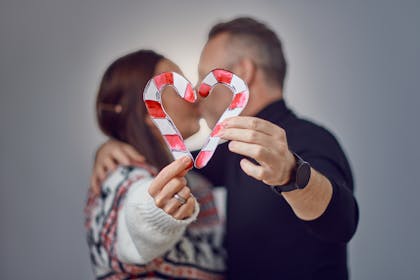 Couple kissing behind a candy cane heart