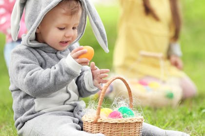 Child in bunny costume with basket of Easter eggs