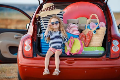 Child in boot of car with holiday packing