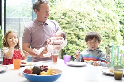 Dad with baby and two children eating vegetables at a table
