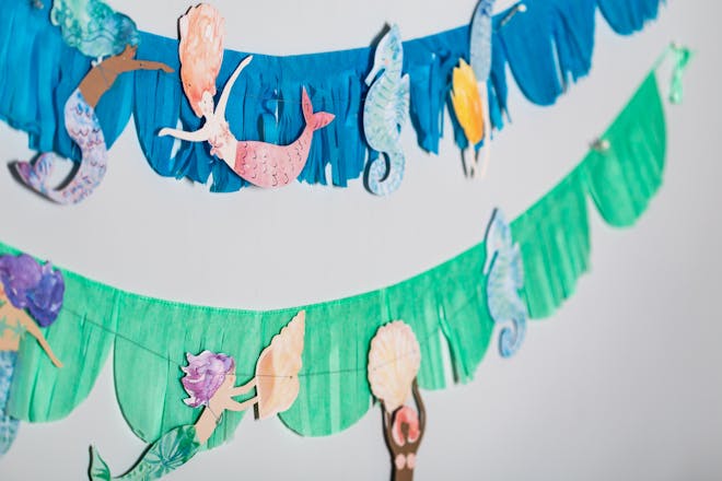 Paper fringed bunting cut to look like seaweed with cutout mermaids and seahorses glued on