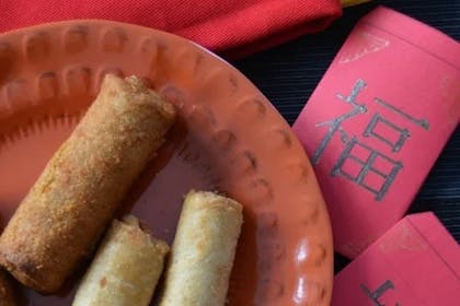 Lucky red envelopes next to a plate of spring rolls