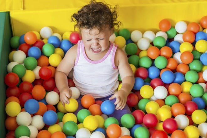 child sitting in ball pit with colourful balls
