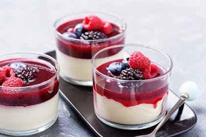 Panna cotta dessert with berry sauce and fresh berries 