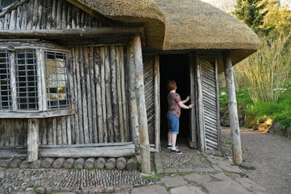 A young boy explores the Bear Hut in the ground of Killerton, Devon