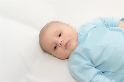 Baby lying on back in blue outfit