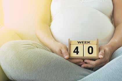 A pregnant woman holding wooden blocks stating week 40
