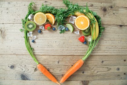 Carrots, lemons, bananas and limes arranged together in shape of heart
