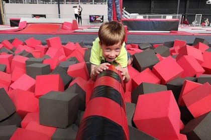 Boy crawling over balance beam across foam pit