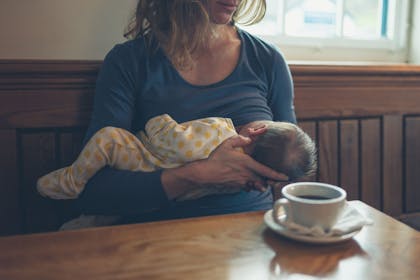 Woman breastfeeding her baby in public sitting at a table in a cafe