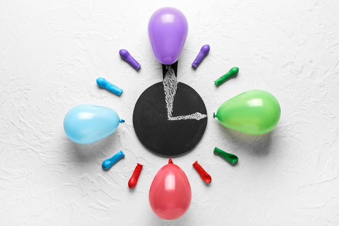 Balloon clock made with purple, green, red and blue balloons set round a chalkboard clock