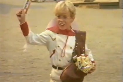 The Milky Bar kid from the retro Milky Bar TV adverts. Blonde boy waves a Milky Bar chocolate bar around.