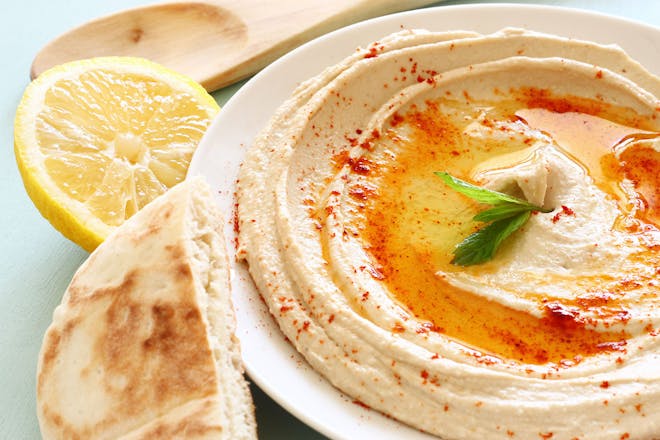 hummus in a bowl with lemon and pita