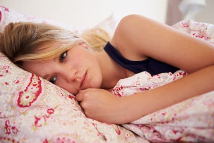 teen looking sad lying in bed