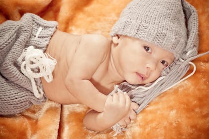 Young baby wearing a matching knitted hat and bottoms