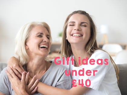 Mum and adult daughter laughing and hugging on sofa text says gift ideas under £40