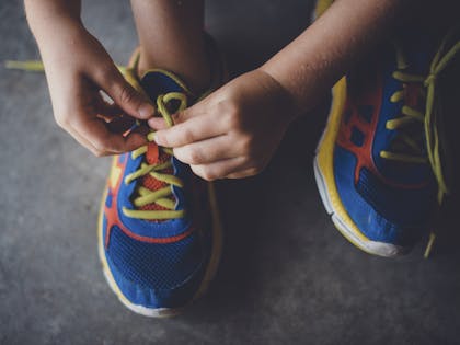 Child lacing up trainers