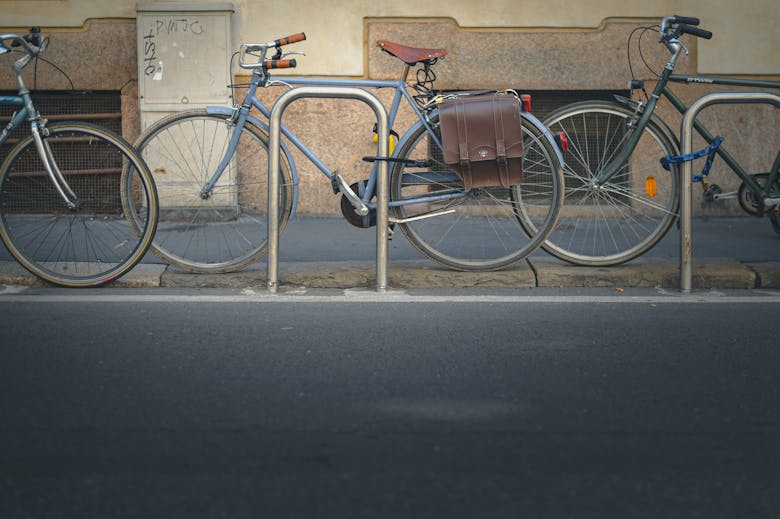 Un vélo bleu avec une sacoche garé contre un poteau