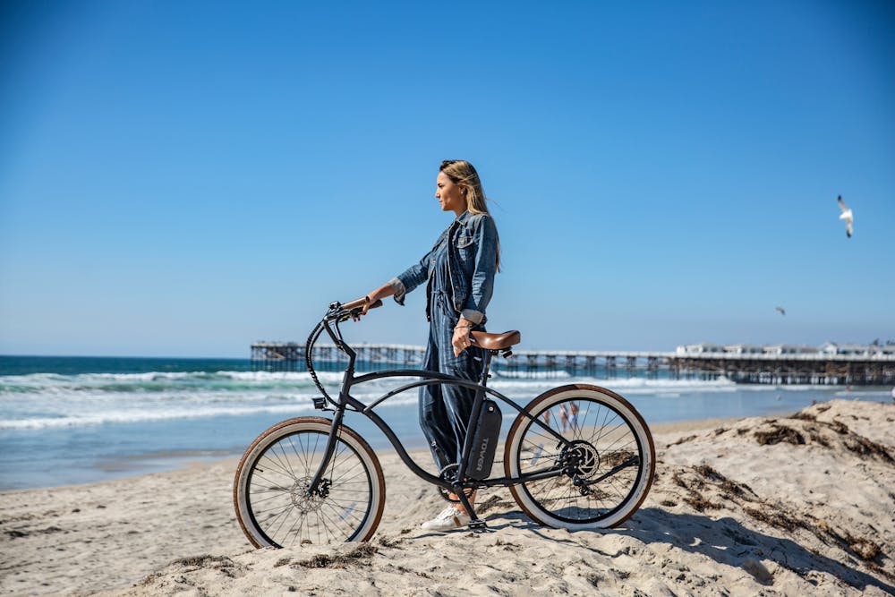 Une femme et son vélo sur une plage, face à la mer