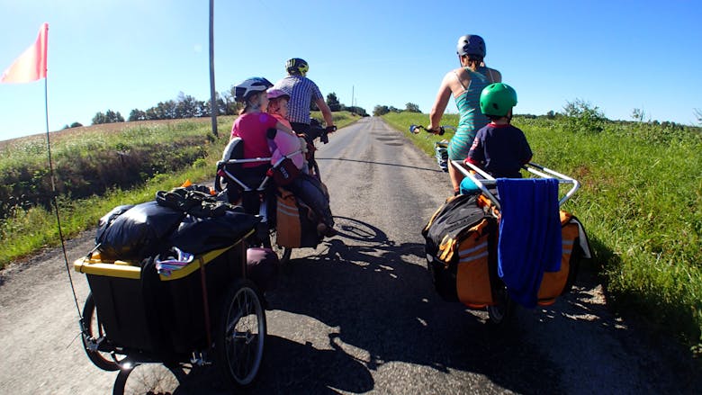 Une famille qui se déplace à vélo avec des remorques vélos