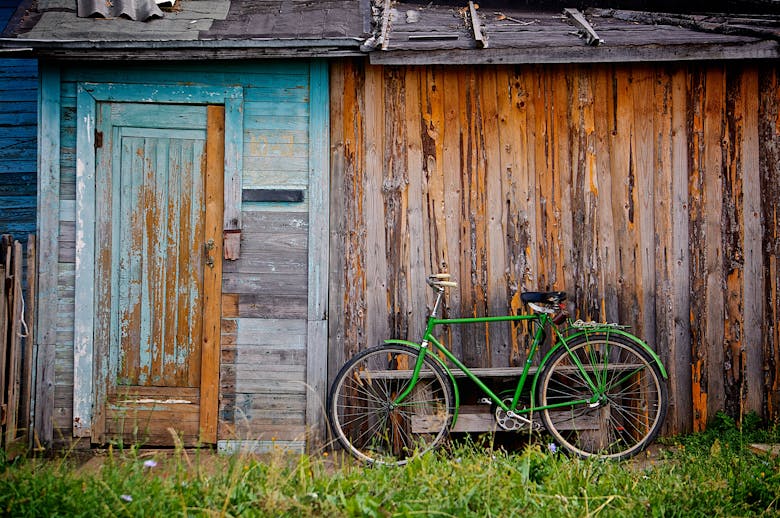 Un vélo vert garé contre une maisonnette en bois