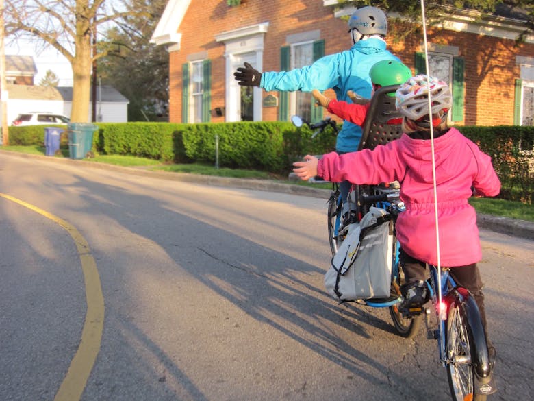 Un parent et ses deux enfants à vélo avec des casques