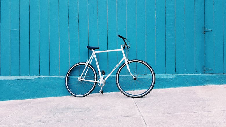 Vélo blanc posé contre un mur bleu