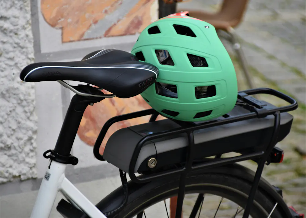 Un casque vélo vert posé sur le porte bagage arrière d'un vélo