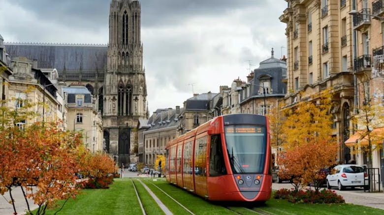 Un tramway orange qui circule devant la cathédrale de Reims