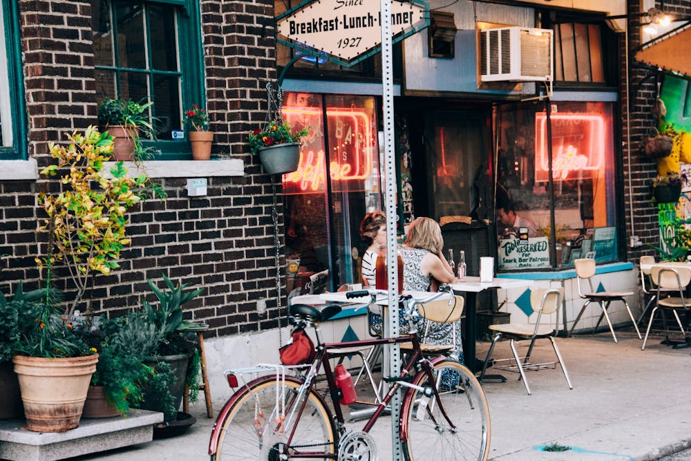 Des personnes qui mangent dans un restaurant en terrasse avec leur vélo garé à côté