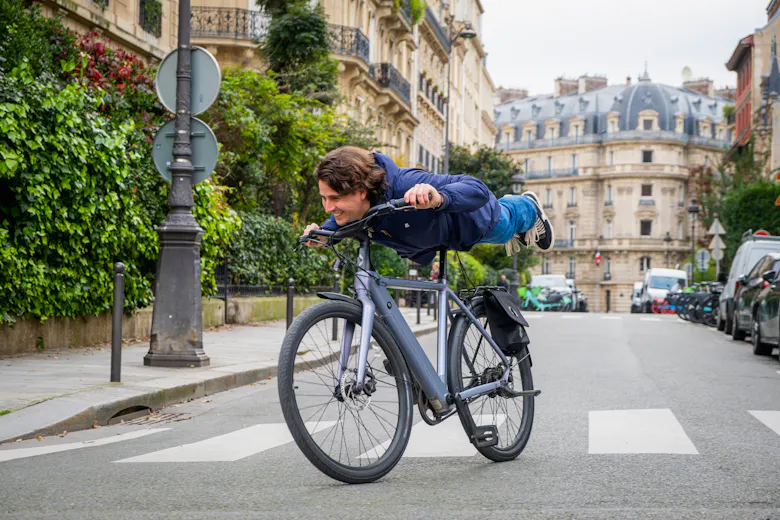 Un jeune homme qui fait la planche sur un vélo électrique dans une rue de Paris