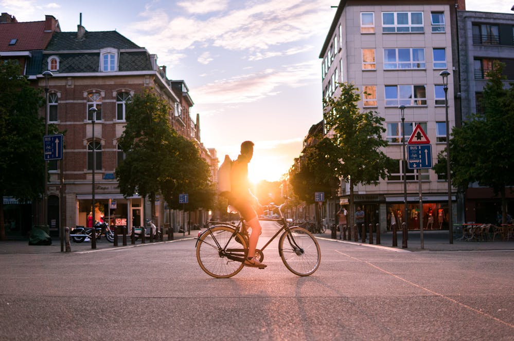 Un cycliste arrêté à un carrefour en ville, qui contemple un coucher de soleil