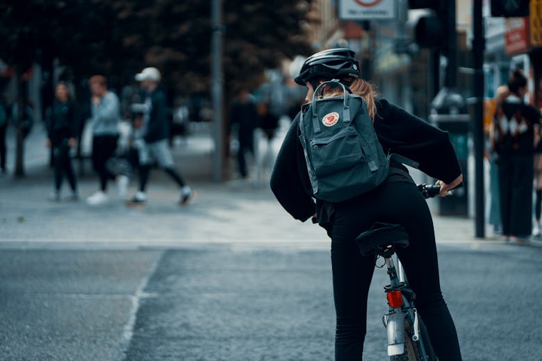 Une femme à vélo avec un casque et un sac à dos