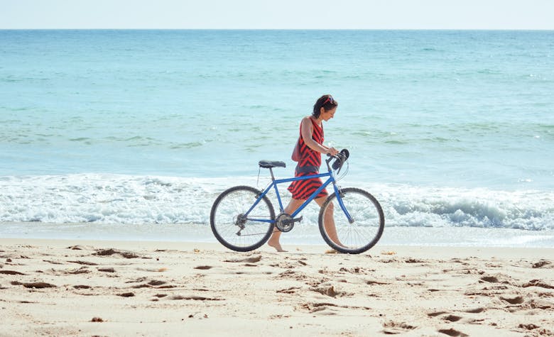 Femme sur la plage en vélo