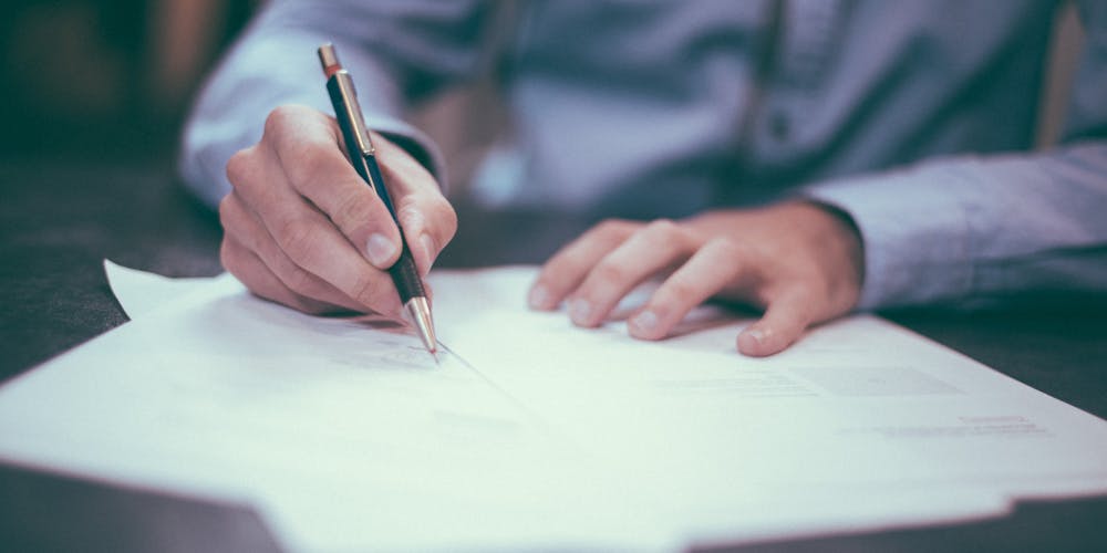 Man with pen completing a number of paper forms