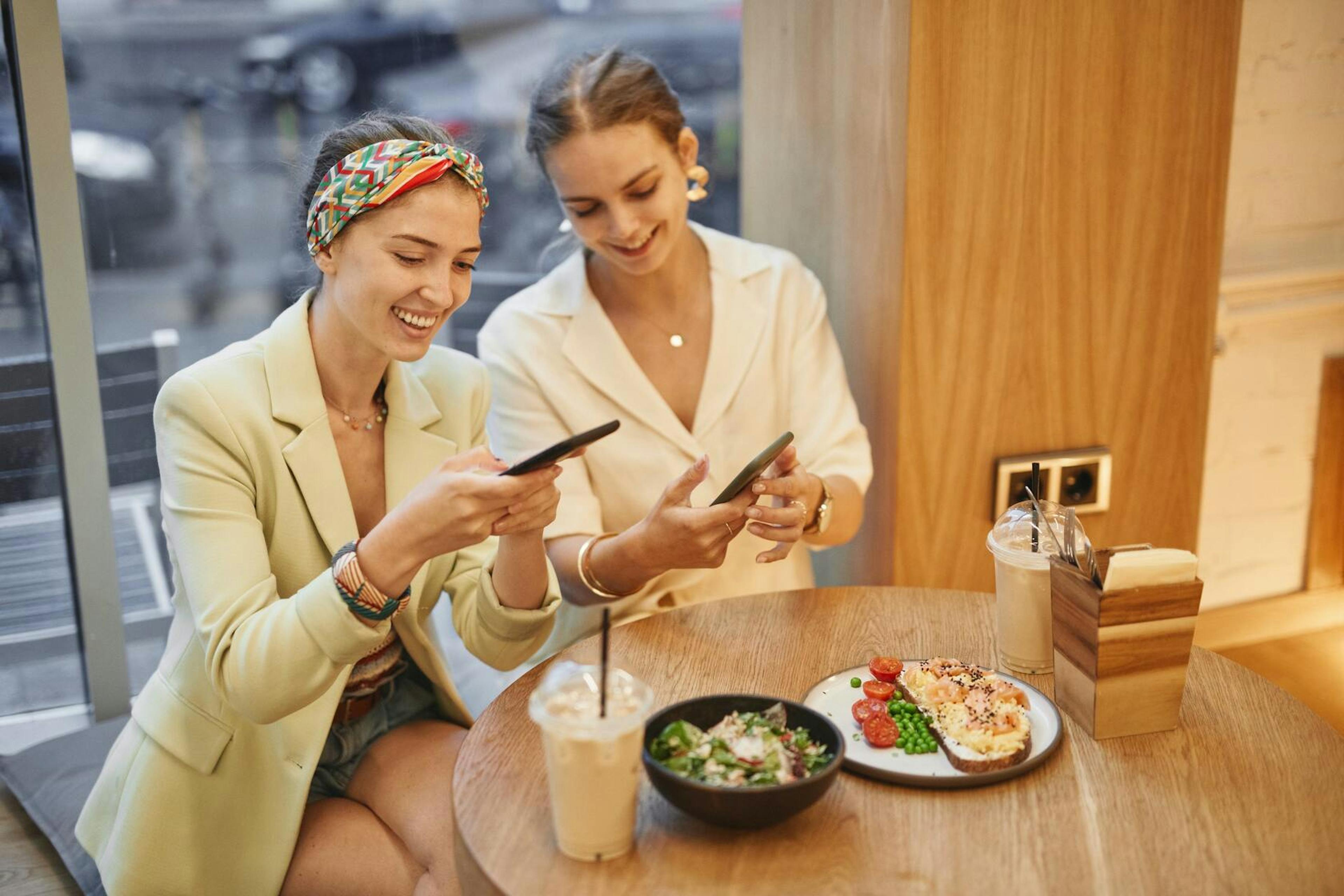 Image of two women taking photos of their food