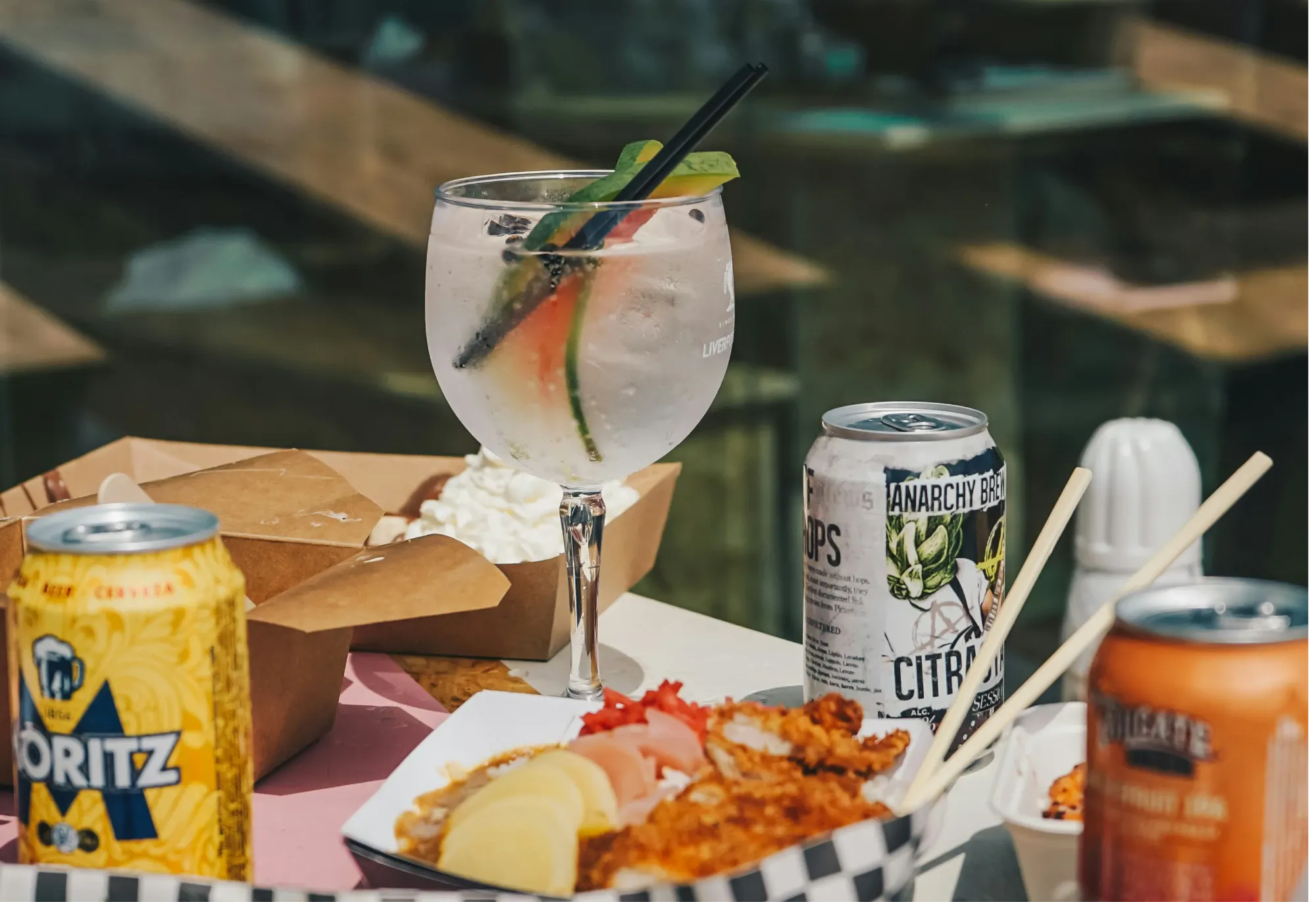 Image of delivered food with a cocktail glass and craft beer cans