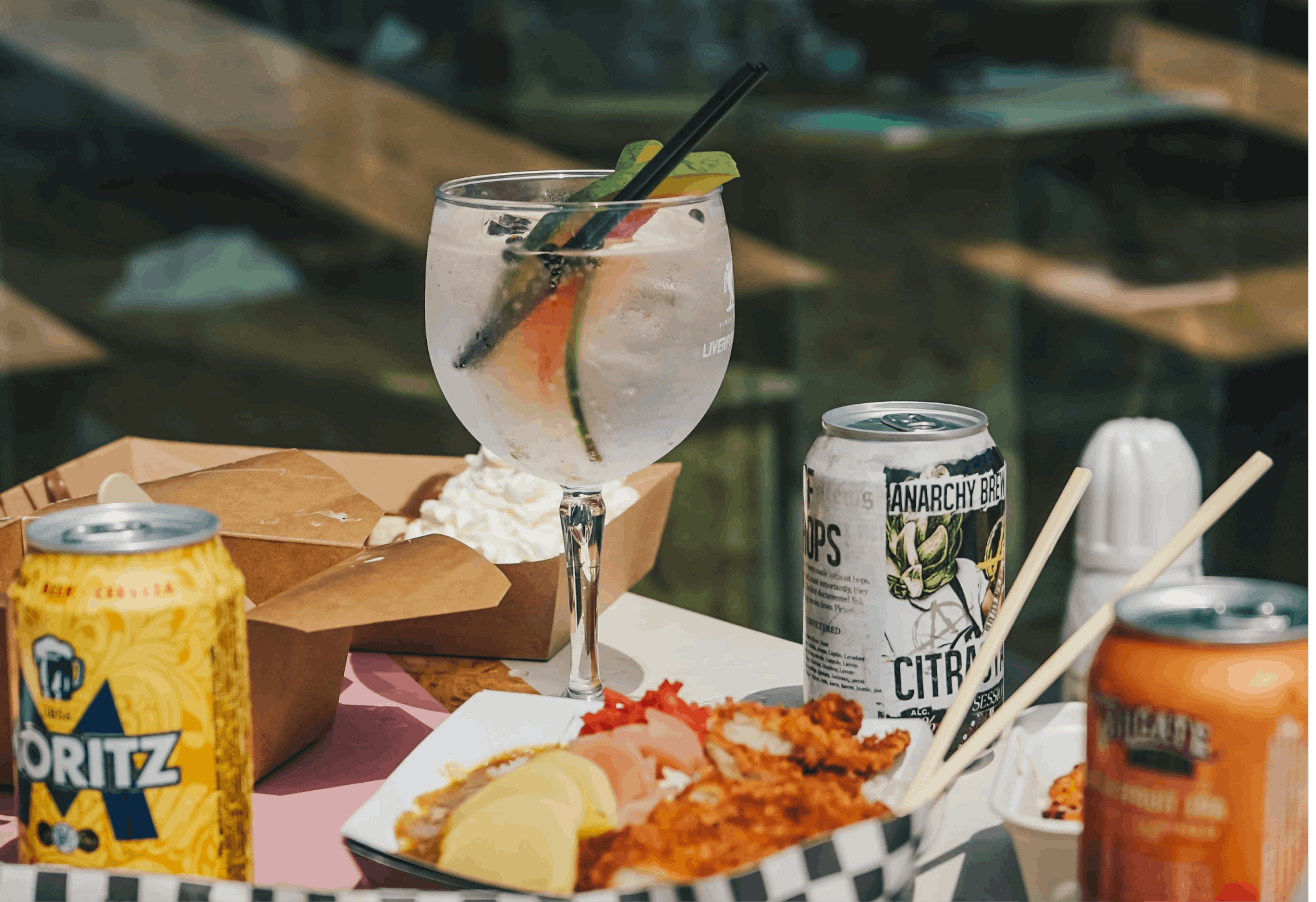 Image of delivered food with a cocktail glass and craft beer cans