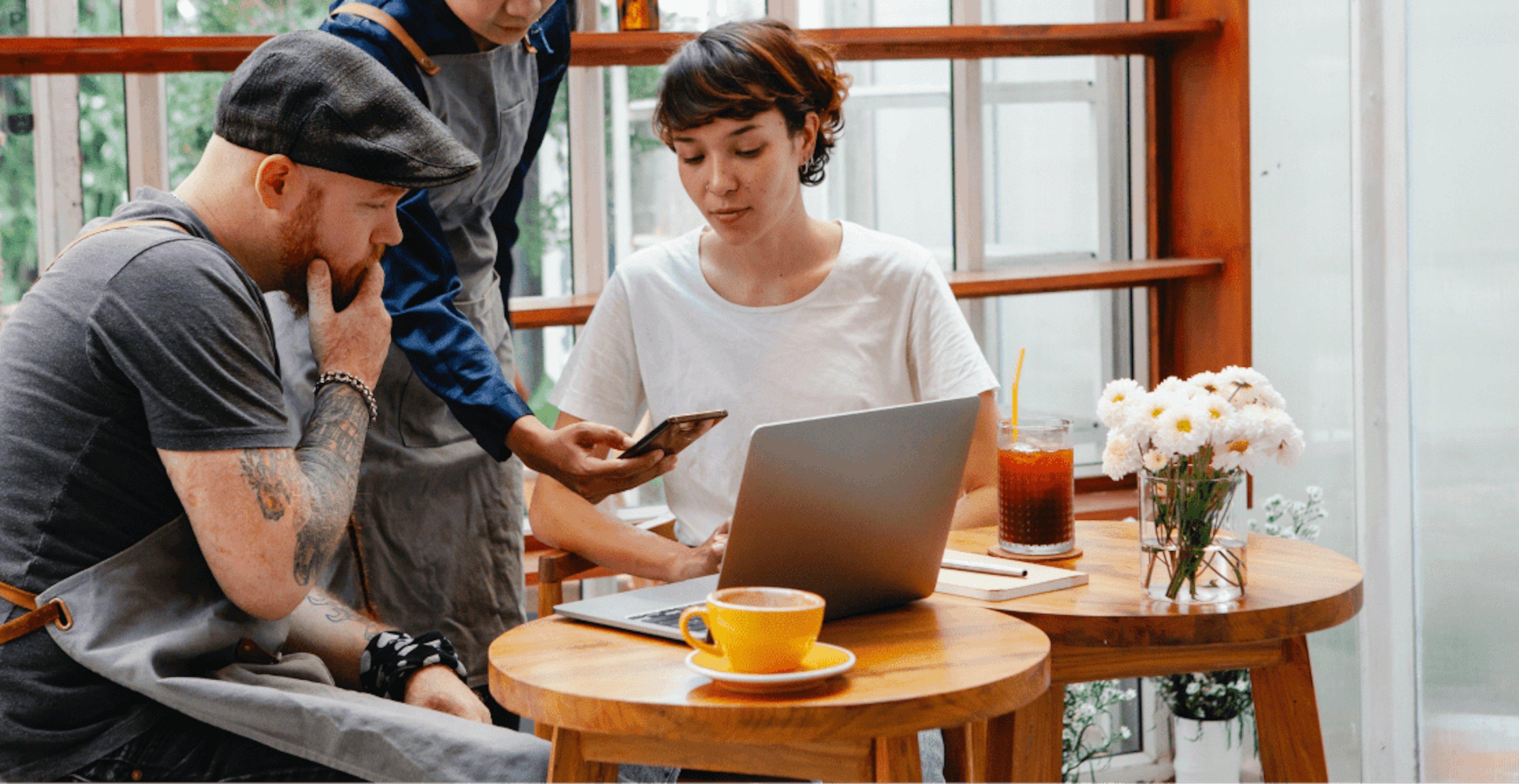 Image of restaurant workers huddling over laptop at a cafe