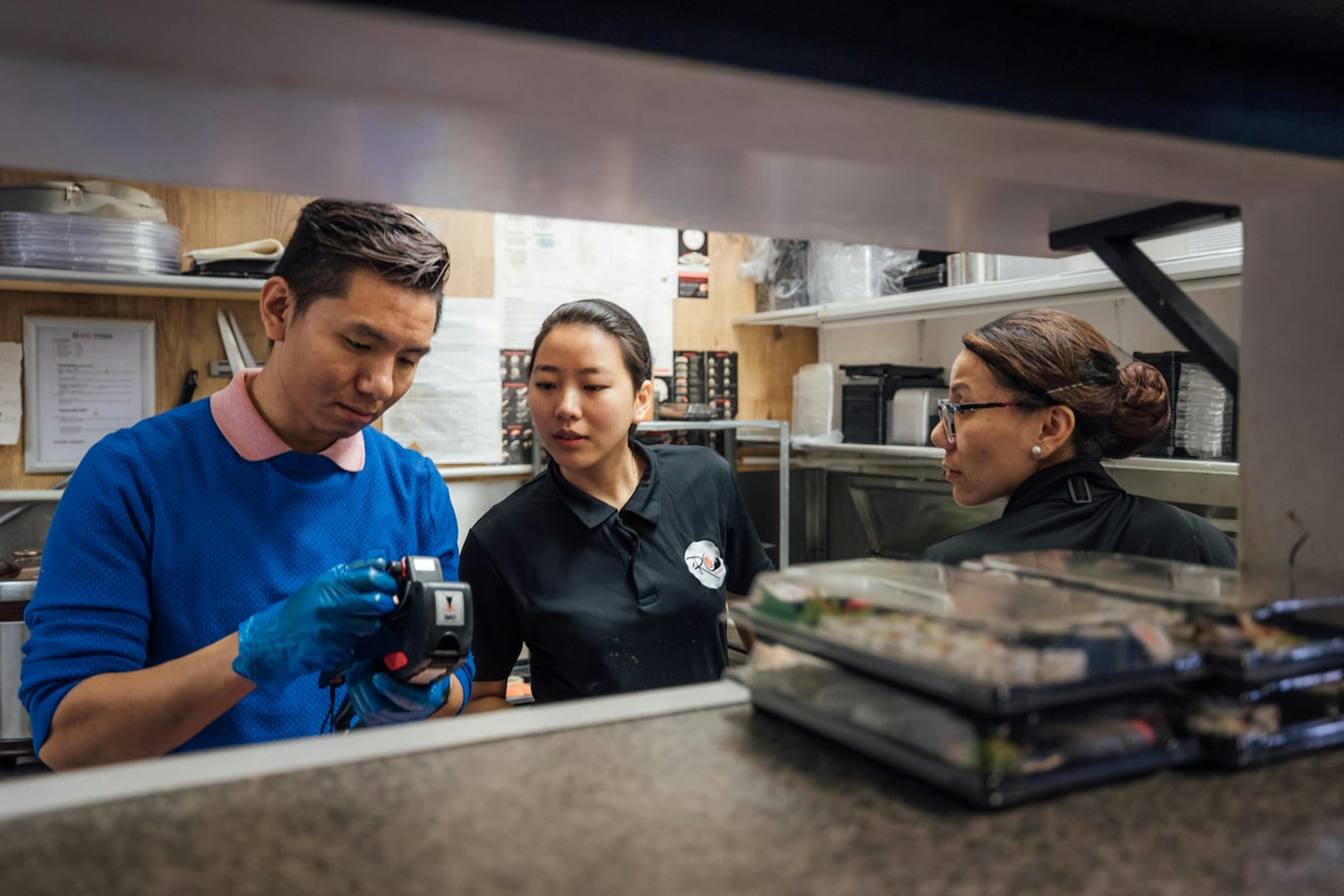 Image of a restaurant team looking at a order ticket printer