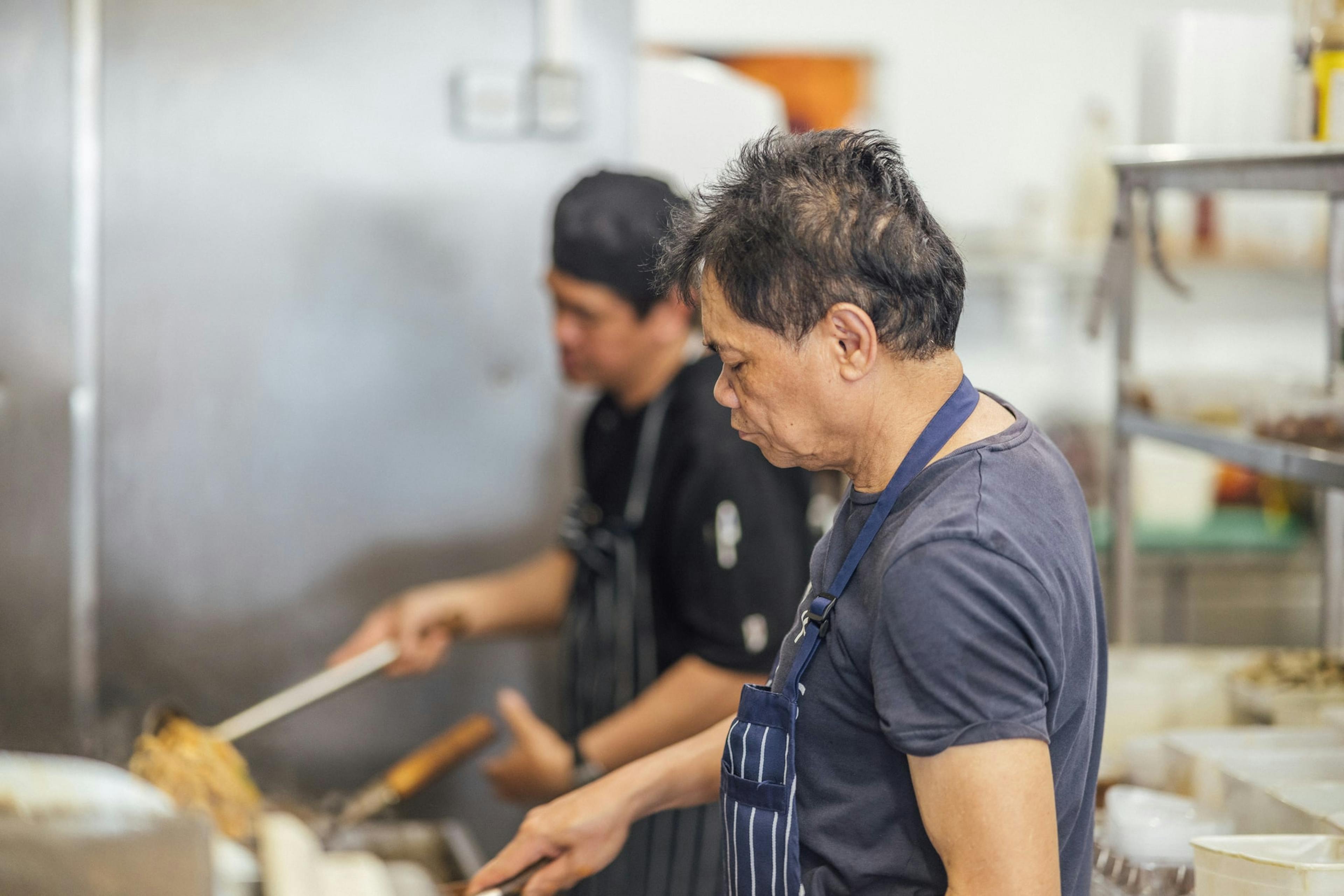 Image of a cook stir-frying at the stove