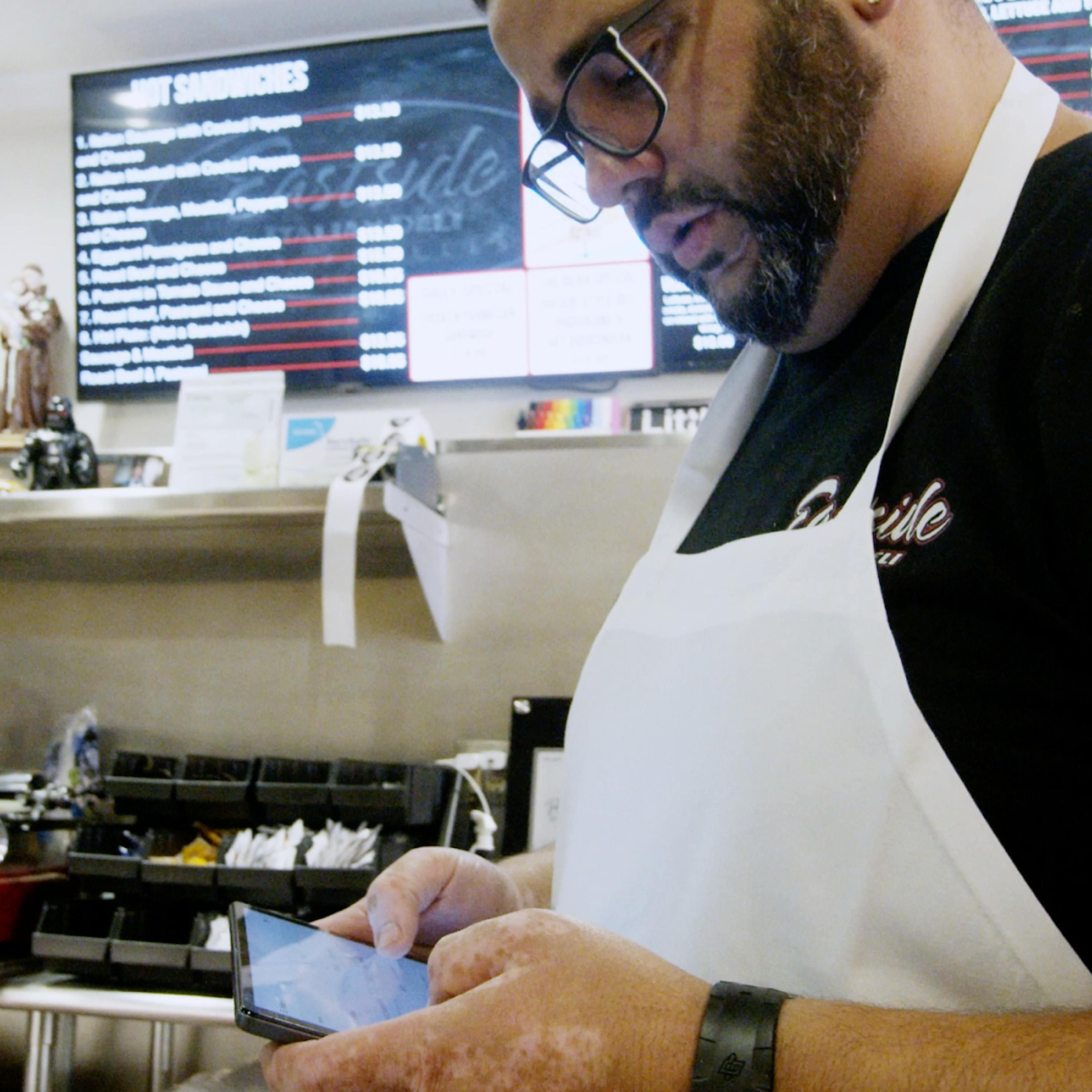 Image of a restaurant owner managing orders through a single tablet