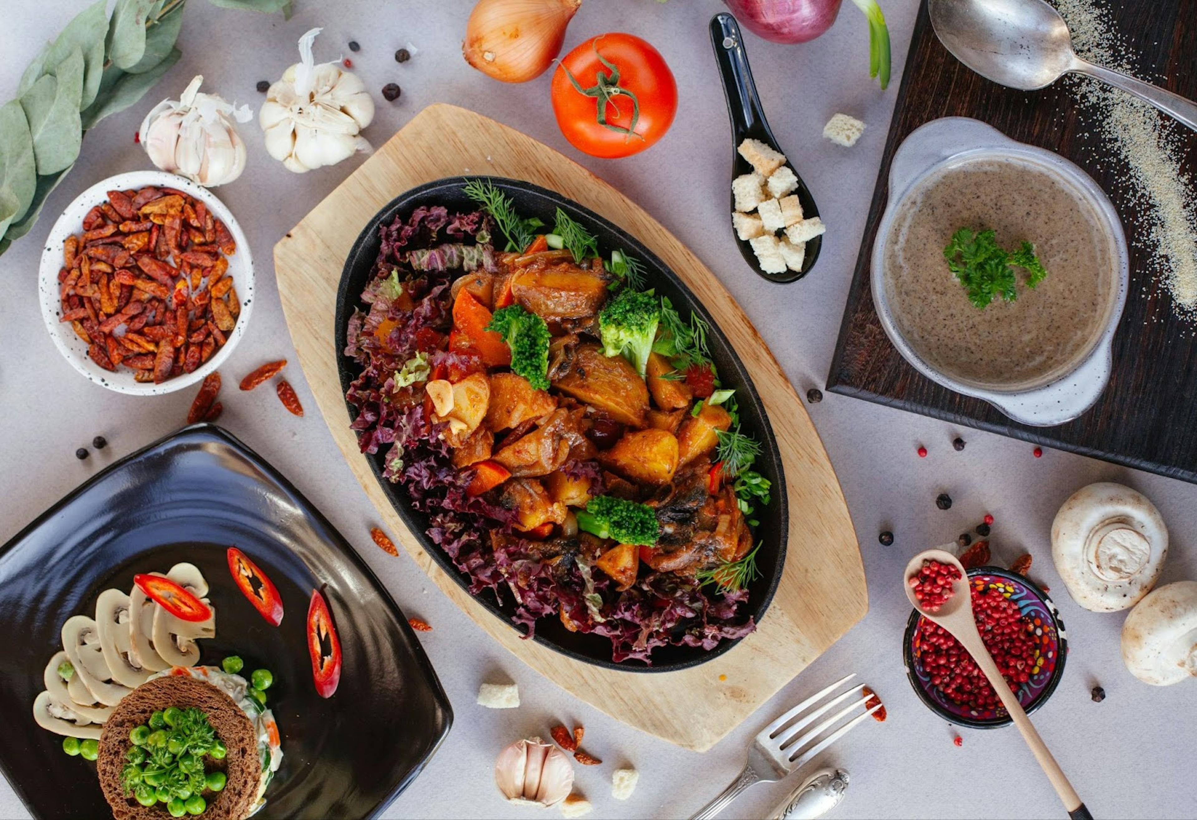 Image of a sizzling plate, mushroom soup and various condiments on the table